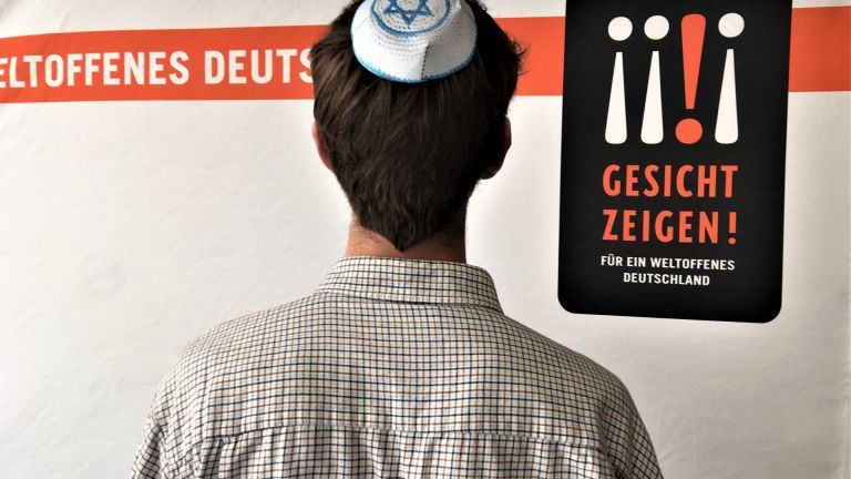 Mann mit Kippa vor dem Logo von Gesicht Zeigen!
