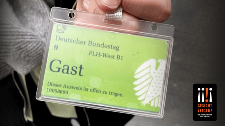 Eine Hand hält den Besucherausweis für den Bundestag